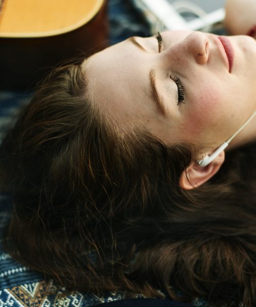 A caucasian woman is listening to music